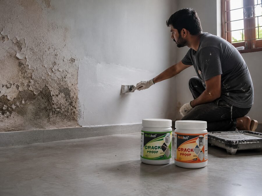 Worker applying Ambhuti Anti-Flaking coating over a damp, peeling wall